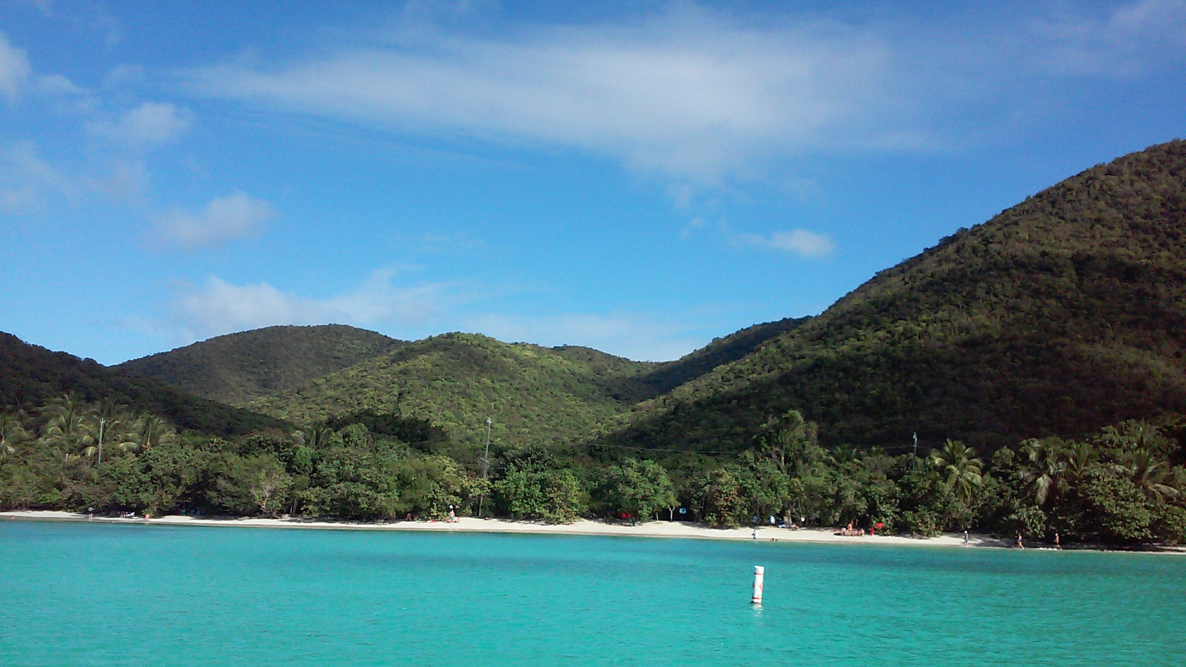 St. John has white sandy beaches lined with palm trees and rimmed with green hills, this photo shows Caneel Bay and Hawksnest Bay