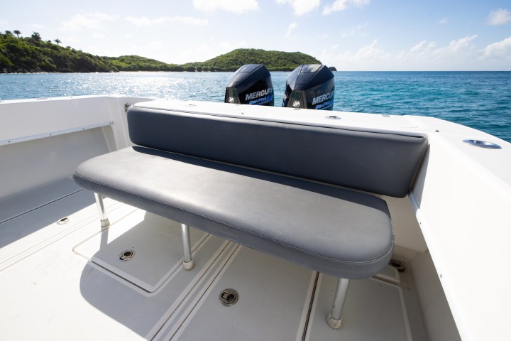 Boat deck with gray bench seat and ocean view with distant islands.