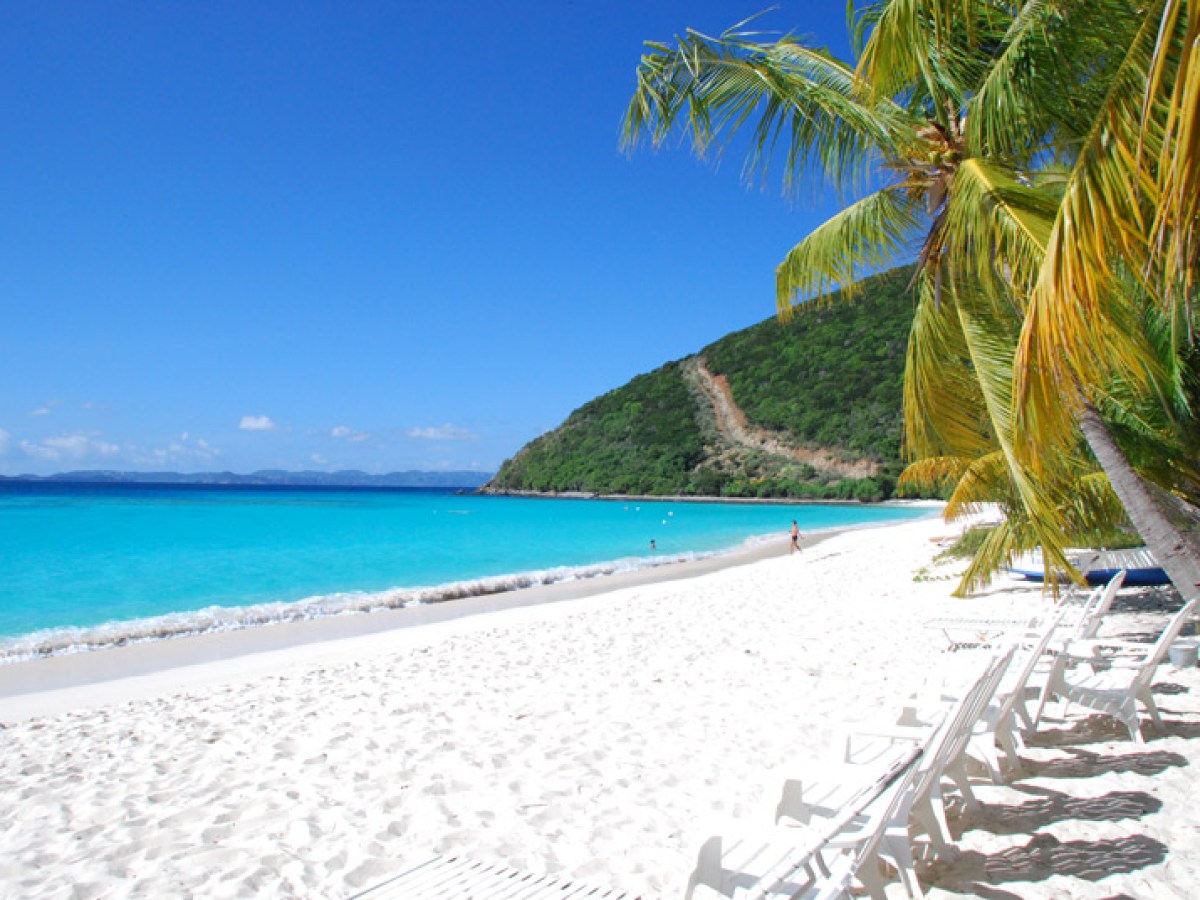 a group of lawn chairs sitting on top of a sandy beach