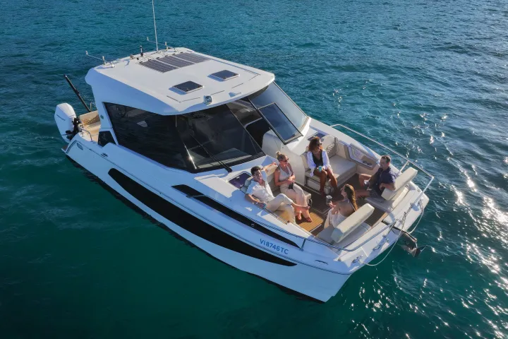 Aerial view of people relaxing on a motorboat in clear blue water.