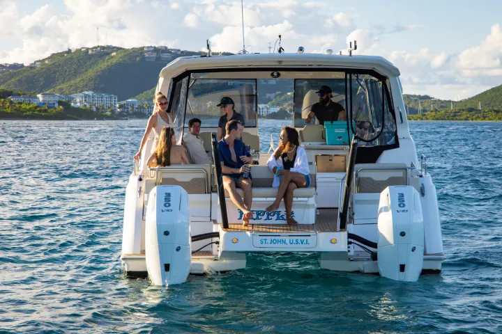 Group of people relaxing on a motorboat near a scenic island.