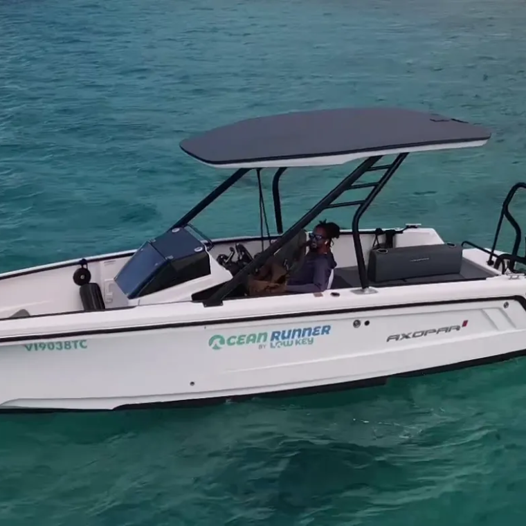White motorboat on clear turquoise water with two people onboard.