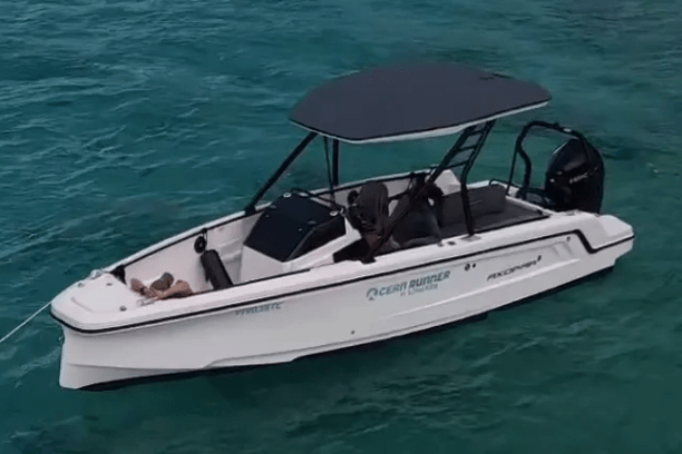 White motorboat on turquoise water with black canopy and engines.